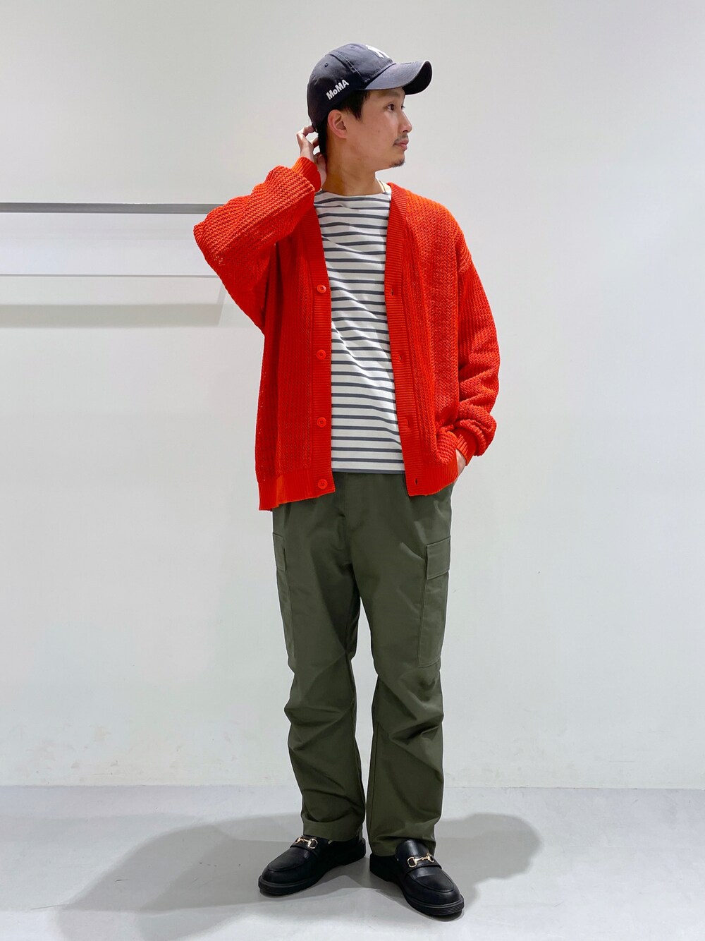 オレンジ系のカーディガン/ボレロ、ベージュ系のTシャツ/カットソー、ブラック系のローファーを着用したメンズの冬コーディネートの1枚目の写真