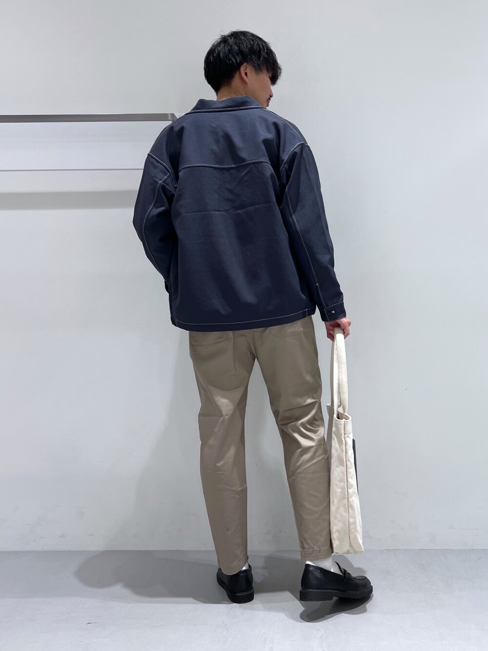 グレー系のチノパンツ、ブラック系のローファー、ブルー系のブルゾンを着用したメンズの春コーディネートの2枚目の写真