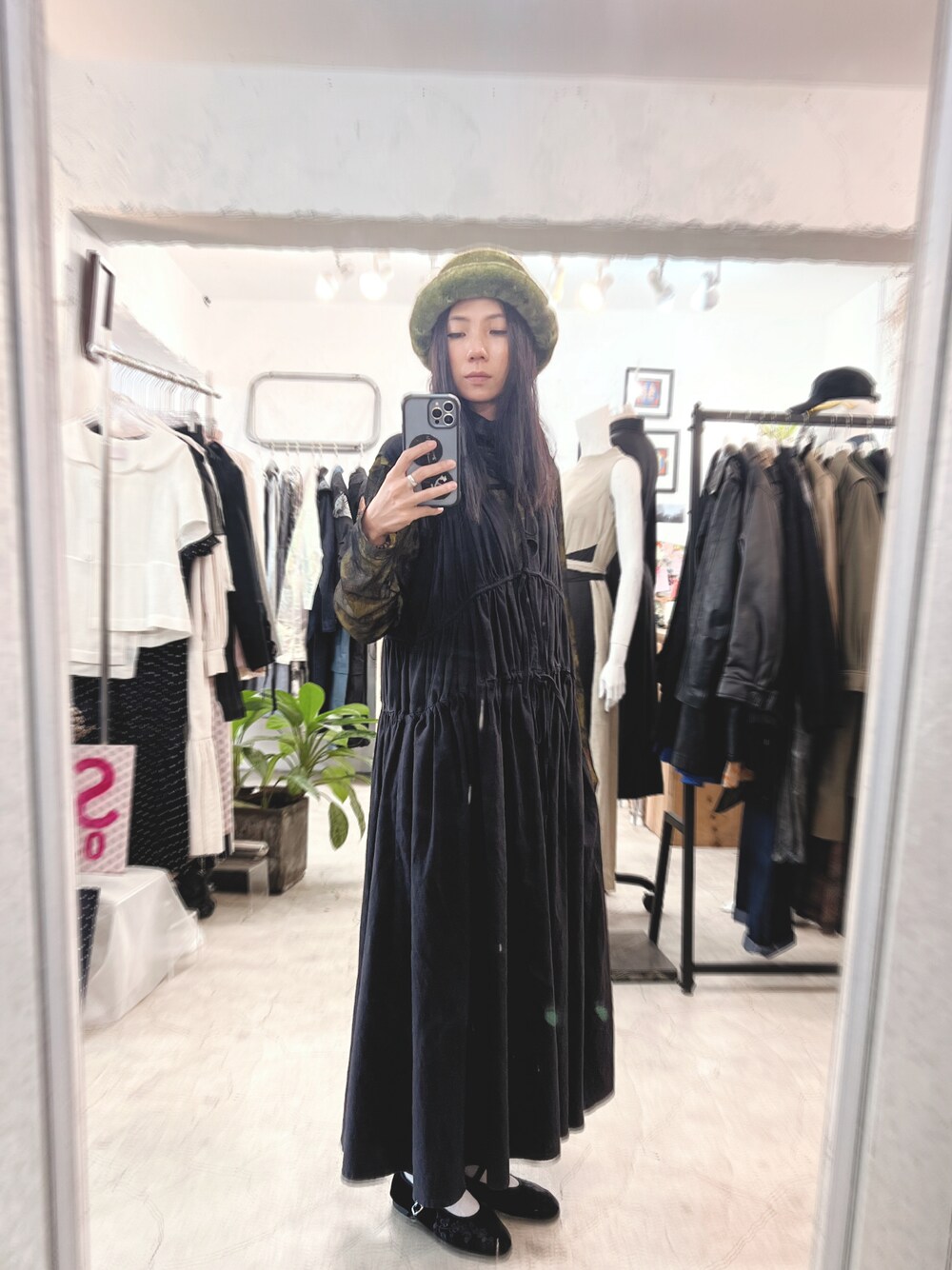 ブラック系のワンピース、グリーン系の帽子を着用したレディースの冬コーディネートの1枚目の写真