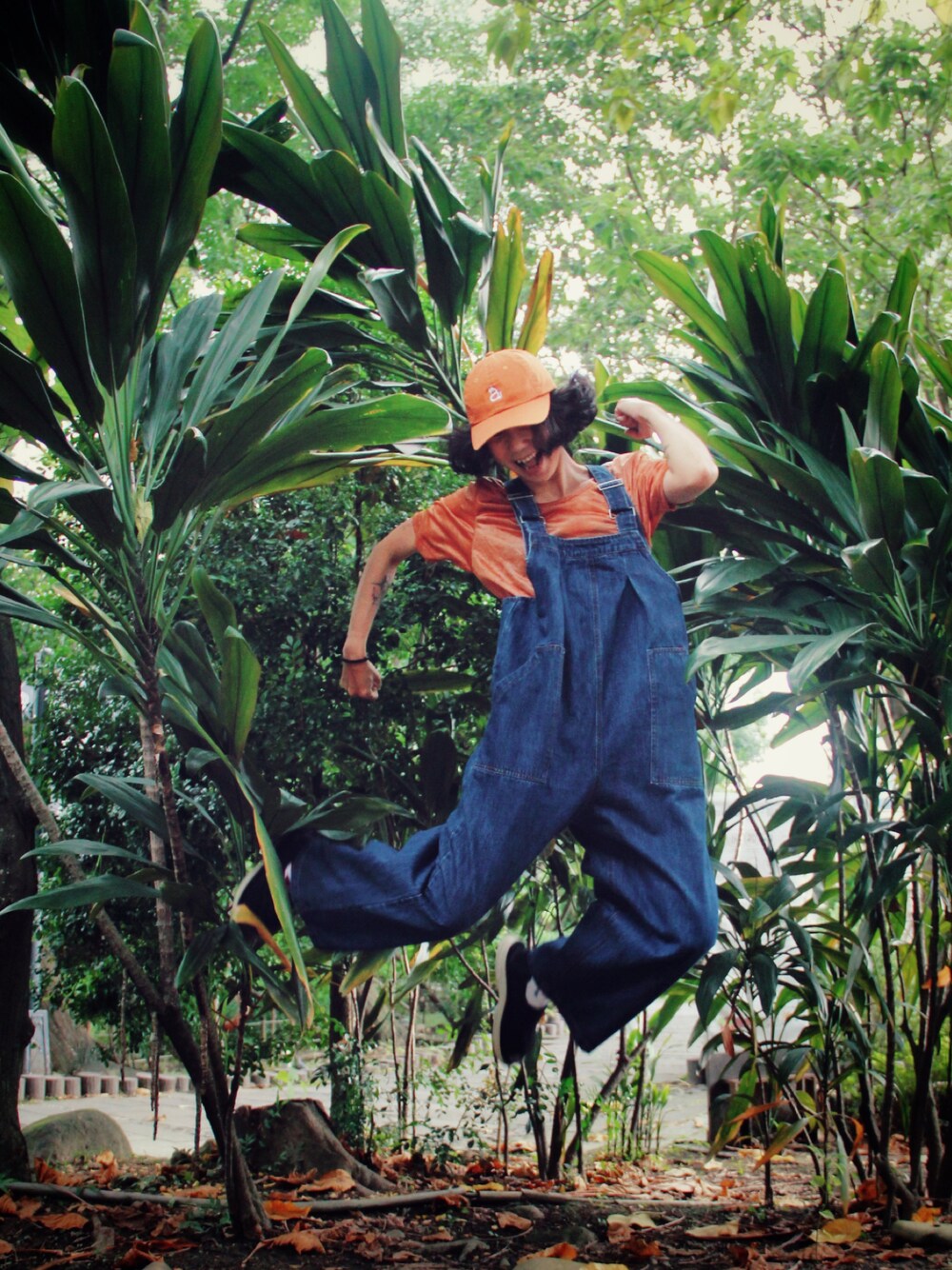 オレンジ系のTシャツ/カットソー、ブルー系のオールインワン・サロペット、オレンジ系のキャップを着用したレディースの夏コーディネートの1枚目の写真