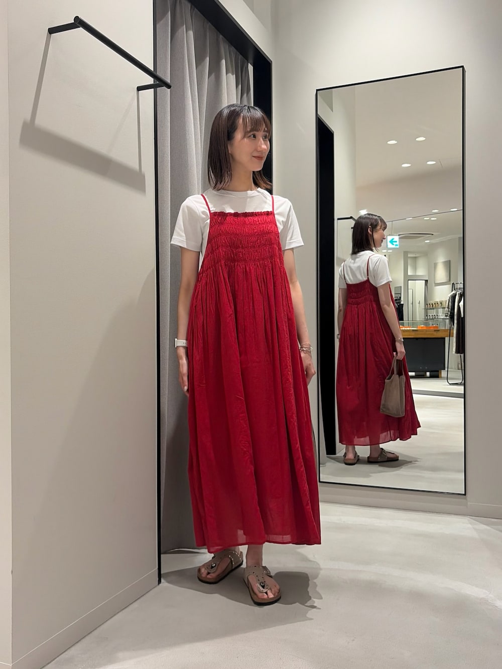 レッド系のワンピース、ホワイト系のTシャツ/カットソー、ベージュ系のサンダルを着用したレディースの春コーディネートの1枚目の写真