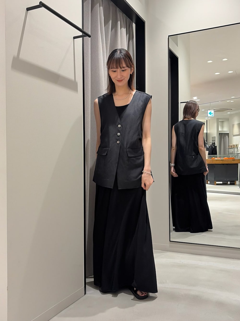 ブラック系のワンピース、ブラック系のダウンベスト、ブラック系のニット/セーターを着用したレディースの春コーディネートの1枚目の写真