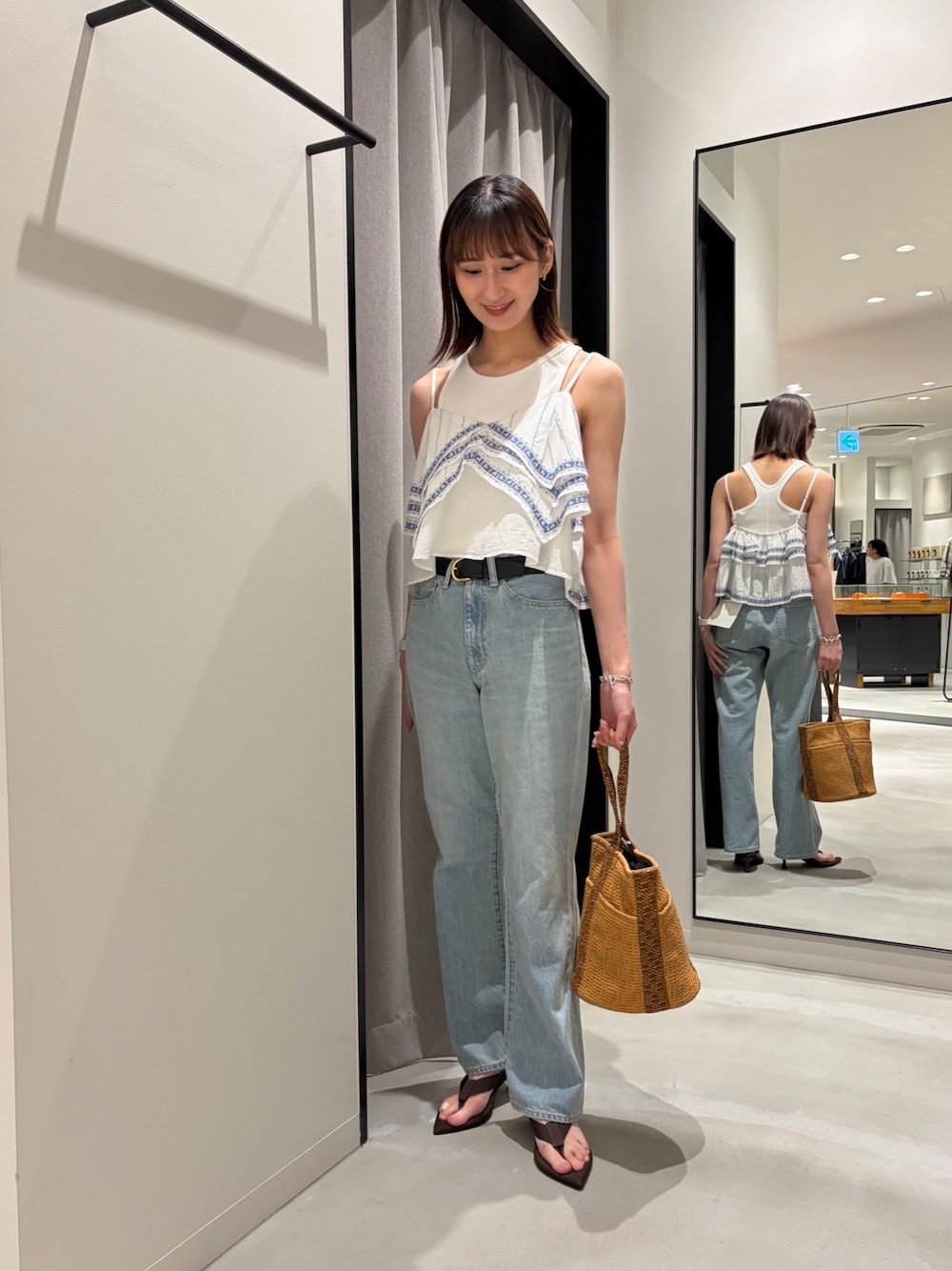ブルー系のデニムパンツ、ブラウン系のサンダル、ベージュ系のバッグを着用したレディースの春コーディネートの1枚目の写真
