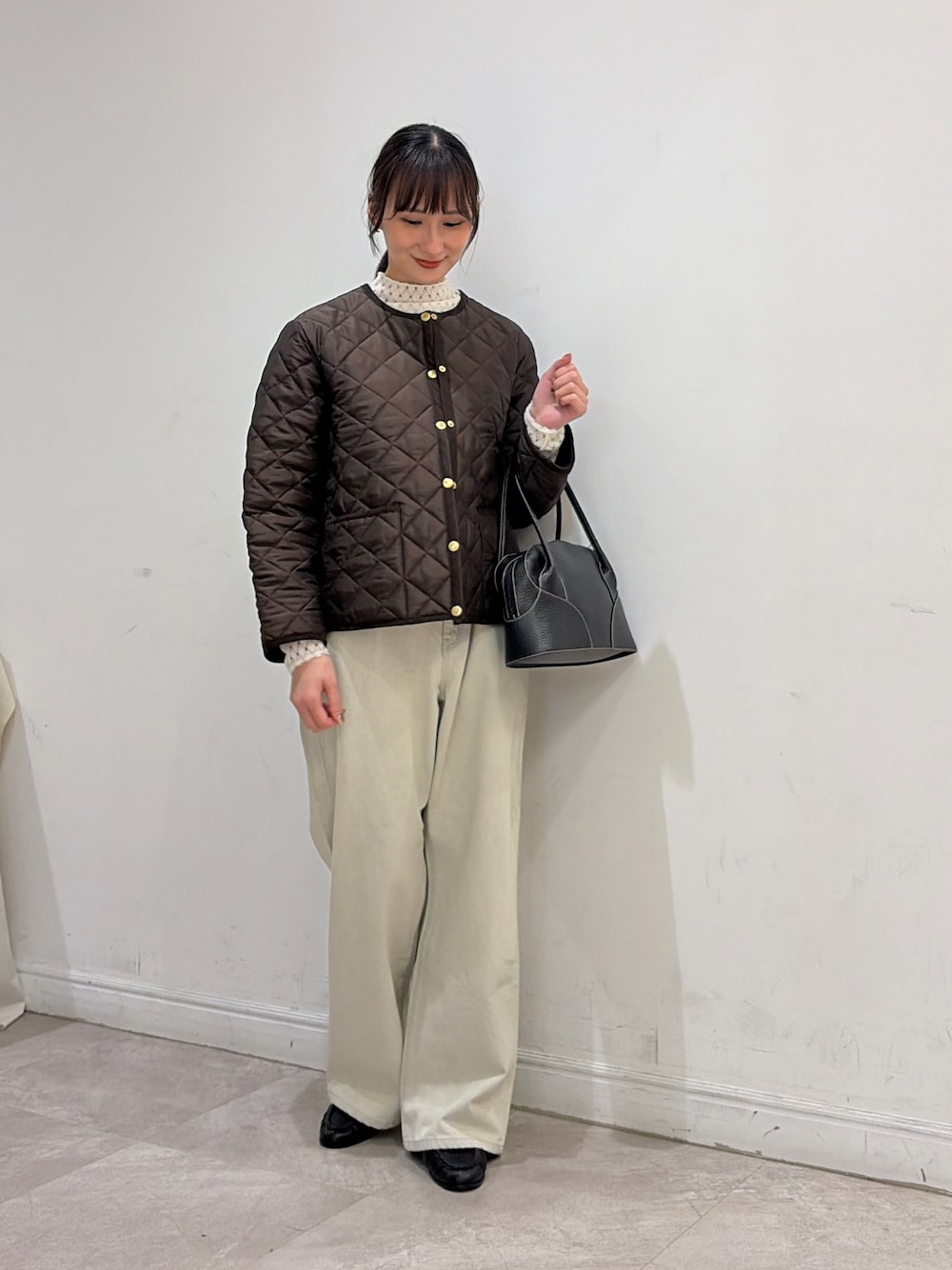 ブラウン系のダウンジャケット/コート、ホワイト系のニット/セーター、ブラック系のバッグを着用したレディースの秋コーディネートの1枚目の写真