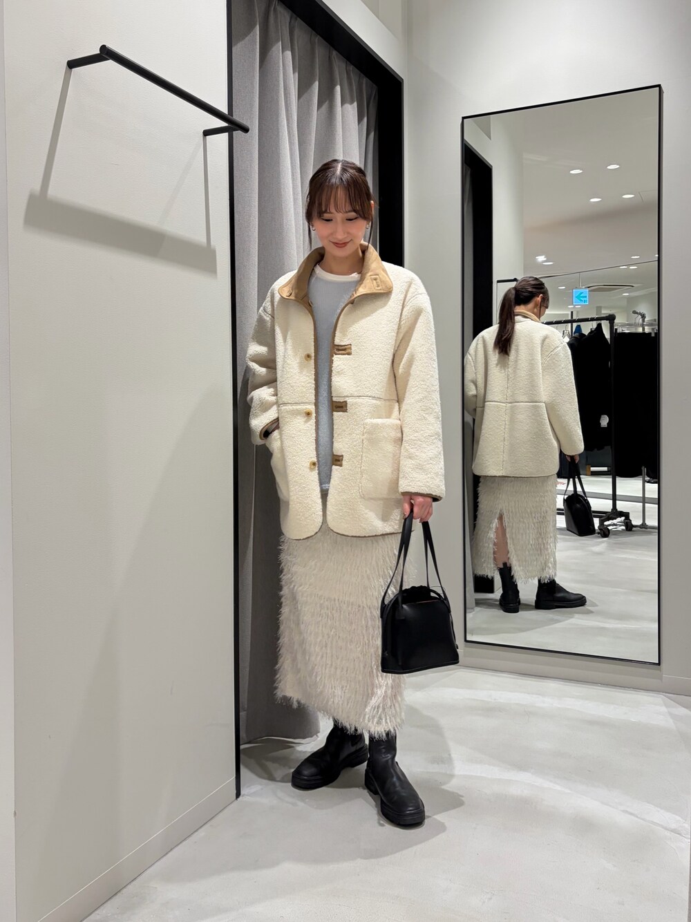 ホワイト系のムートンコート、ブルー系のニット/セーター、ホワイト系のTシャツ/カットソーを着用したレディースの冬コーディネートの1枚目の写真