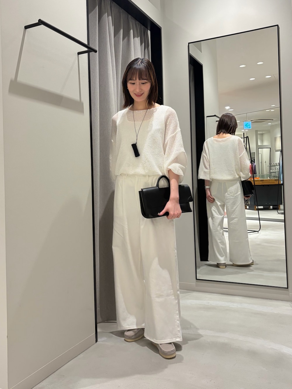 ホワイト系のデニムパンツ、ブラック系のハンドバッグ、グレー系のその他シューズを着用したレディースの春コーディネートの1枚目の写真