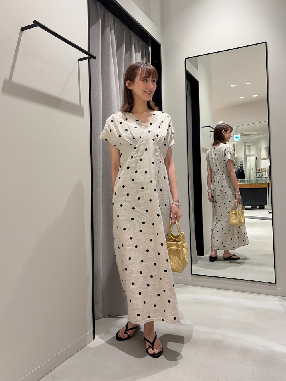 ブラック系のサンダル、ベージュ系のワンピース、ベージュ系のトートバッグを着用したレディースの夏コーディネートの1枚目の写真