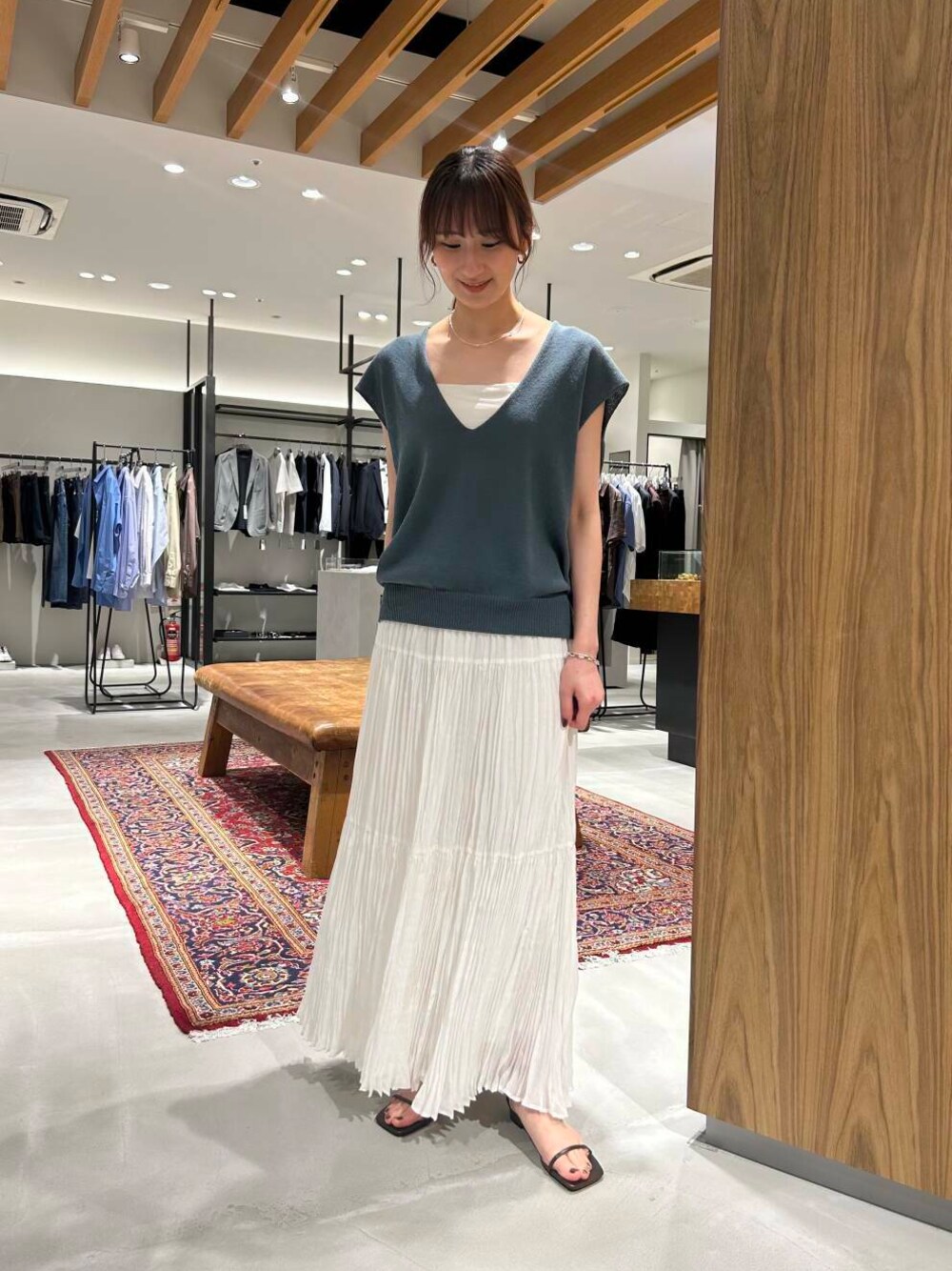 ホワイト系のスカート、ブラウン系のサンダル、ブルー系のベストを着用したレディースの春コーディネートの1枚目の写真