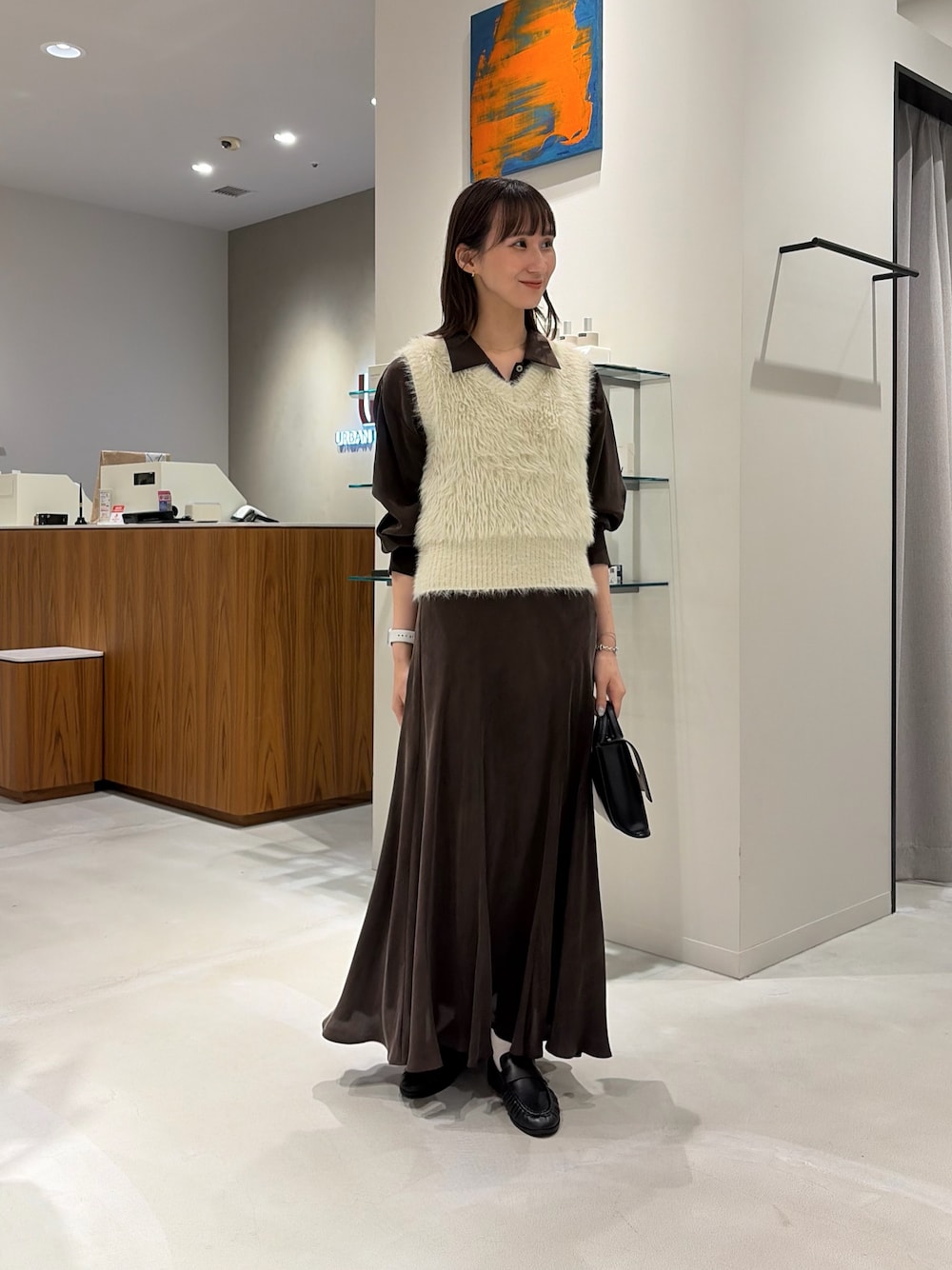 ブラウン系のシャツ/ブラウス、ブラウン系のスカート、ブラック系のハンドバッグを着用したレディースの秋コーディネートの1枚目の写真
