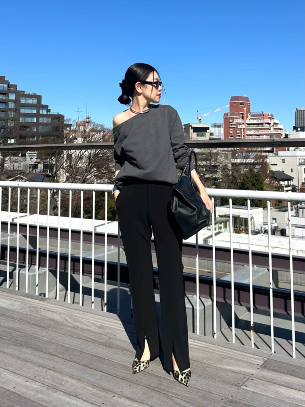 ブラック系のボストンバッグ、グレー系のTシャツ/カットソー、ブラック系のスラックスを着用したレディースの春コーディネートの1枚目の写真