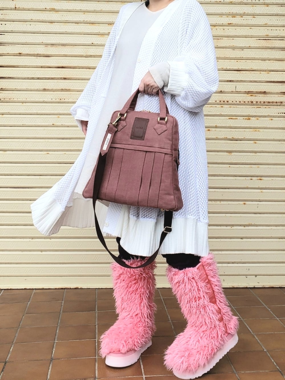 ピンク系のブーツ、ベージュ系のカーディガン/ボレロ、ピンク系のショルダーバッグを着用したレディースの冬コーディネートの1枚目の写真