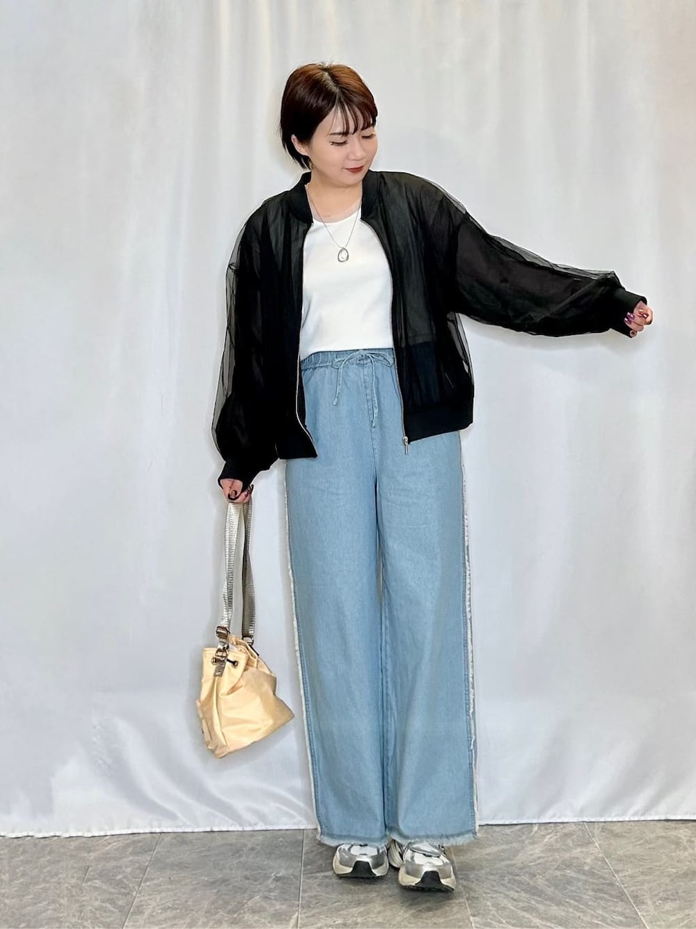 ブラック系のブルゾン、ホワイト系のTシャツ/カットソー、ブルー系のデニムパンツを着用したレディースの春コーディネートの1枚目の写真