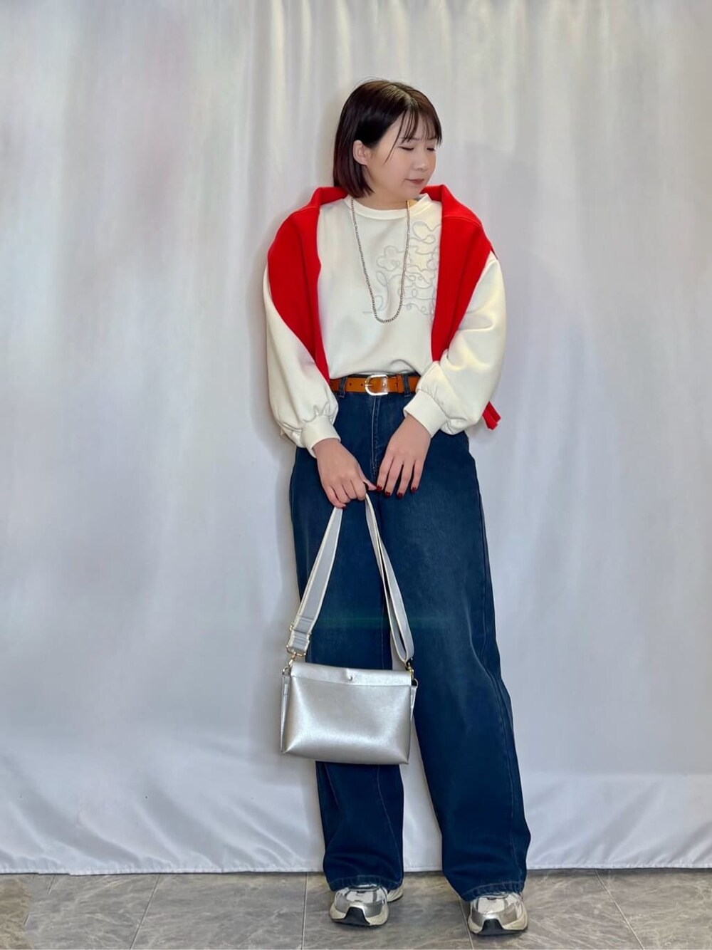 オレンジ系のニット/セーター、ホワイト系のTシャツ/カットソー、ブルー系のデニムパンツを着用したレディースの冬コーディネートの1枚目の写真