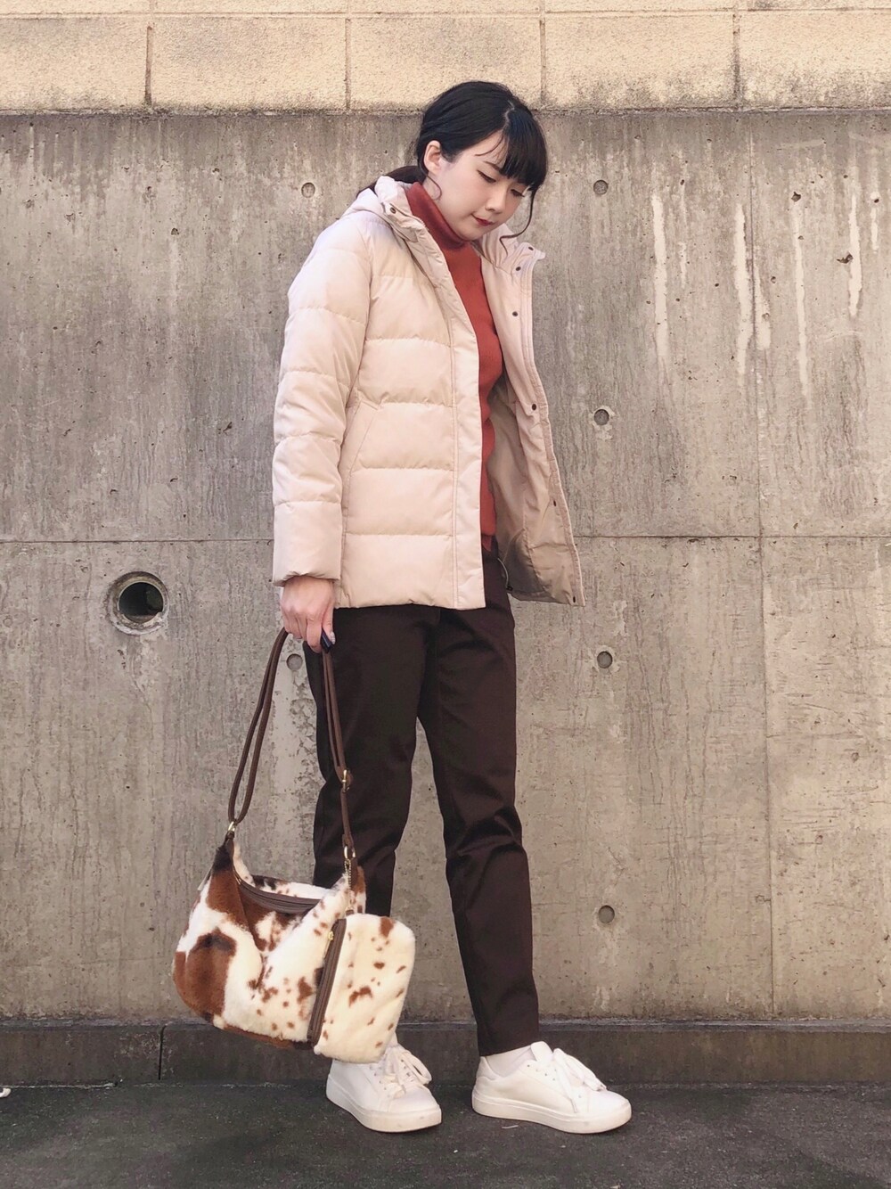 ベージュ系のダウンジャケット/コート、ピンク系のニット/セーター、ホワイト系のスニーカーを着用したレディースの冬コーディネートの1枚目の写真