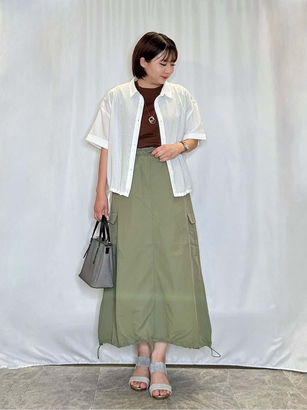 ホワイト系のシャツ/ブラウス、ブラウン系のTシャツ/カットソー、グリーン系のスカートを着用したレディースの夏コーディネートの1枚目の写真