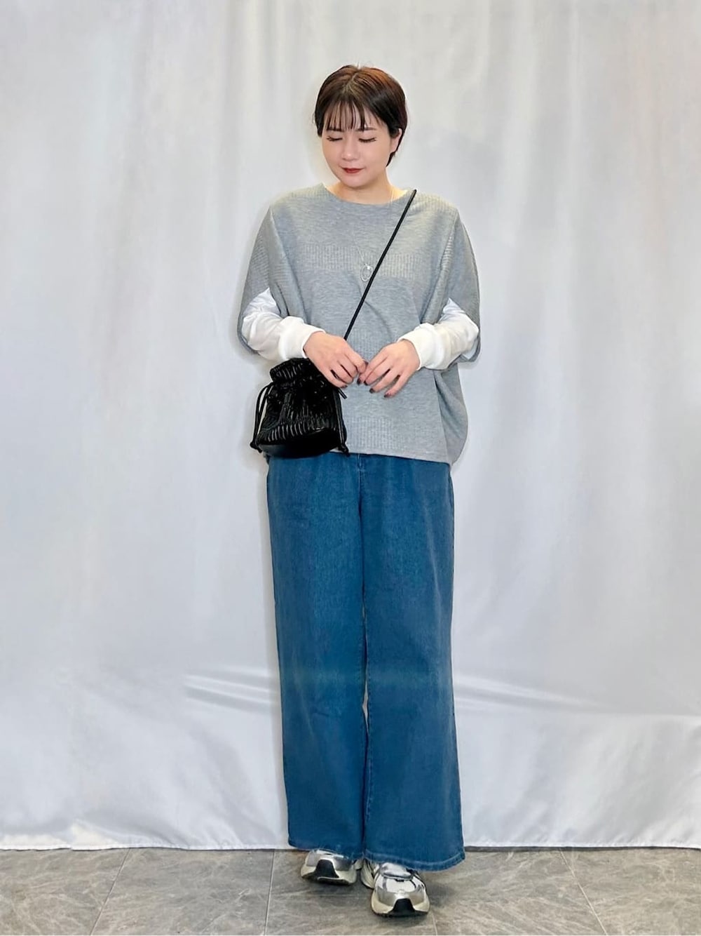 グレー系のその他トップス、ブルー系のデニムパンツ、ブラック系のショルダーバッグを着用したレディースの春コーディネートの1枚目の写真