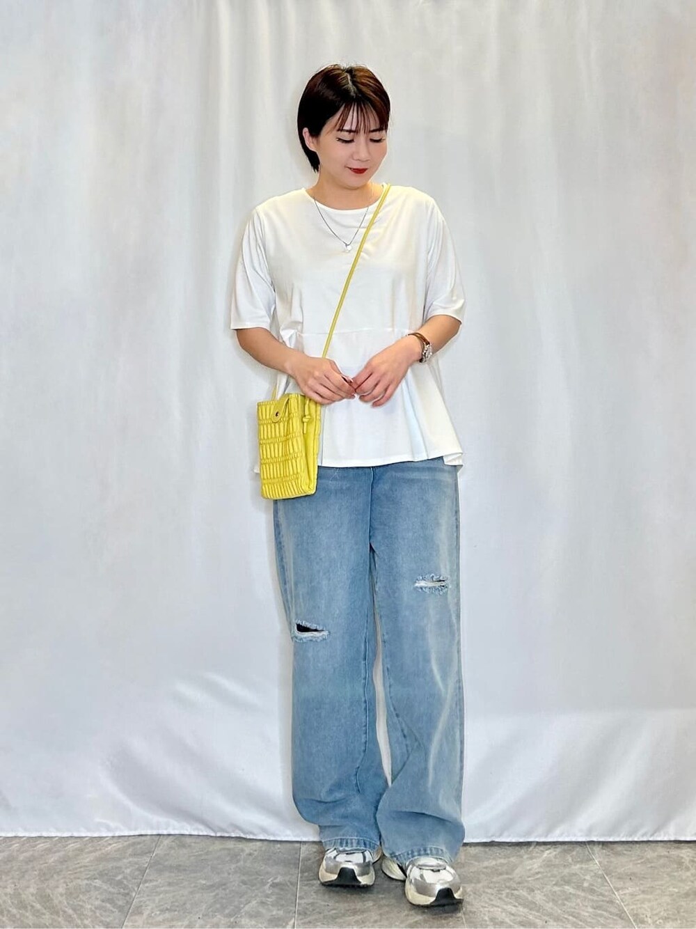 ホワイト系のTシャツ/カットソー、ブルー系のデニムパンツ、イエロー系のショルダーバッグを着用したレディースの春コーディネートの1枚目の写真