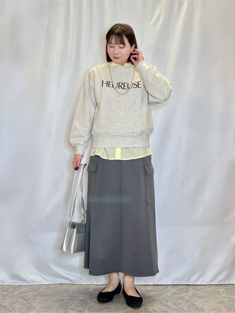 グレー系のスウェット、イエロー系のシャツ/ブラウス、グレー系のスカートを着用したレディースの冬コーディネートの1枚目の写真