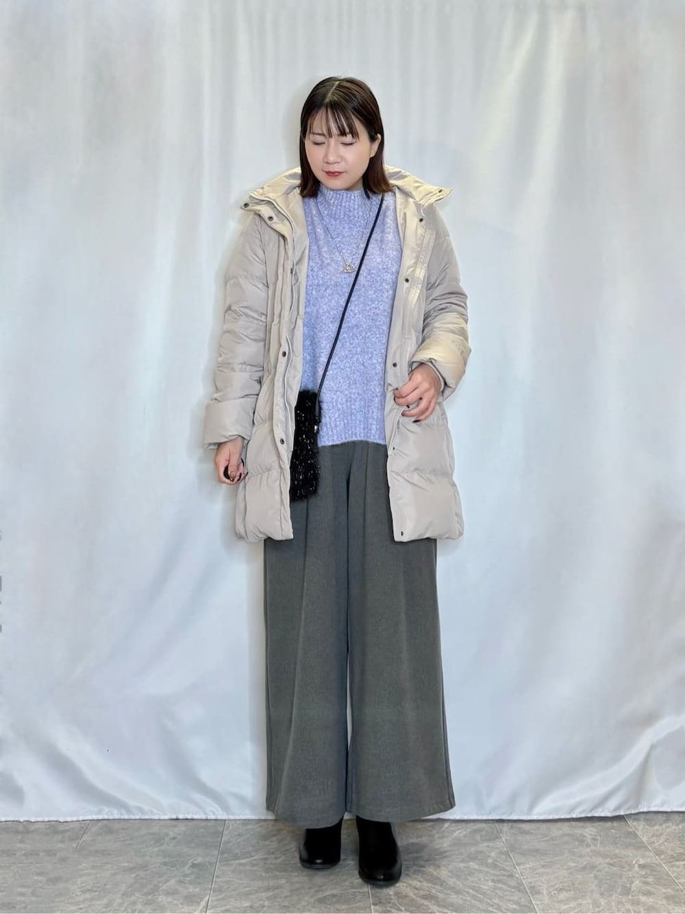 ベージュ系のダウンジャケット/コート、ブルー系のニット/セーター、グレー系のその他パンツを着用したレディースの冬コーディネートの1枚目の写真