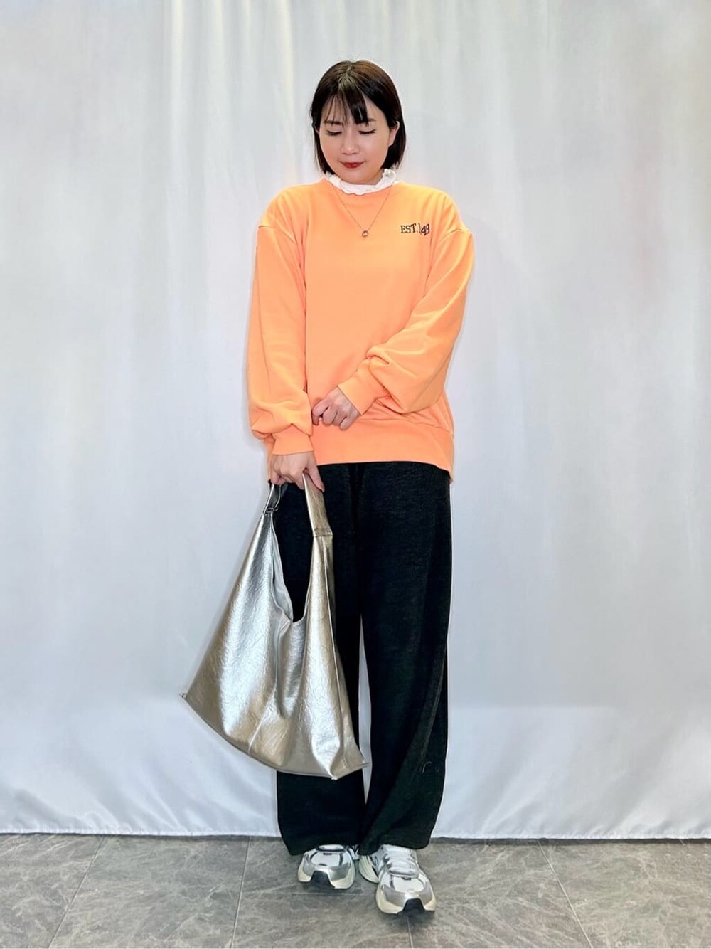 オレンジ系のスウェット、ホワイト系のTシャツ/カットソー、ブラック系のその他パンツを着用したレディースの冬コーディネートの1枚目の写真