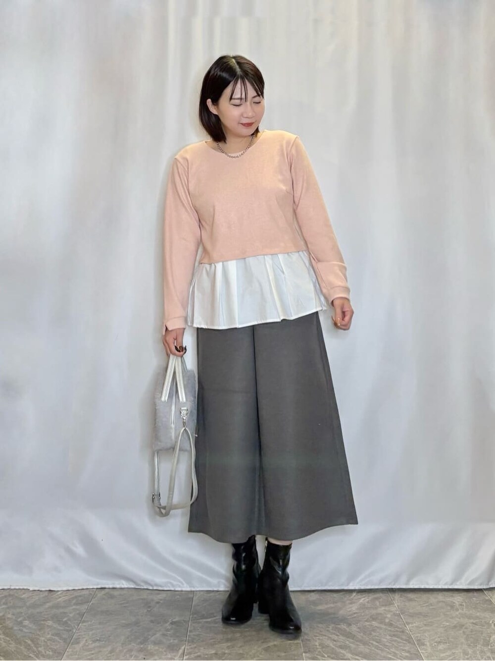 オレンジ系のTシャツ/カットソー、ブラック系のブーツ、グレー系のショルダーバッグを着用したレディースの秋コーディネートの1枚目の写真