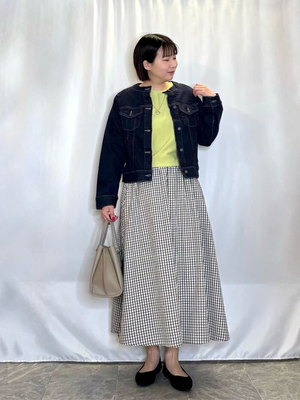 グレー系のワンピース、ブルー系のデニムジャケット、グリーン系のニット/セーターを着用したレディースの春コーディネートの1枚目の写真