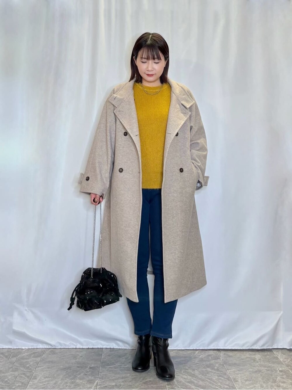 ベージュ系のその他アウター、イエロー系のニット/セーター、ブルー系のその他パンツを着用したレディースの冬コーディネートの1枚目の写真