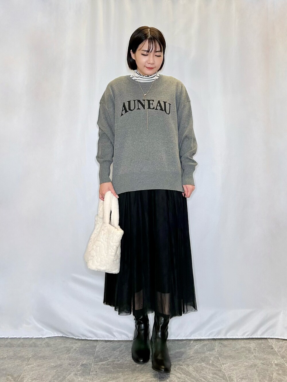 ベージュ系のトートバッグ、ブラック系のブーツ、グレー系のニット/セーターを着用したレディースの秋コーディネートの1枚目の写真