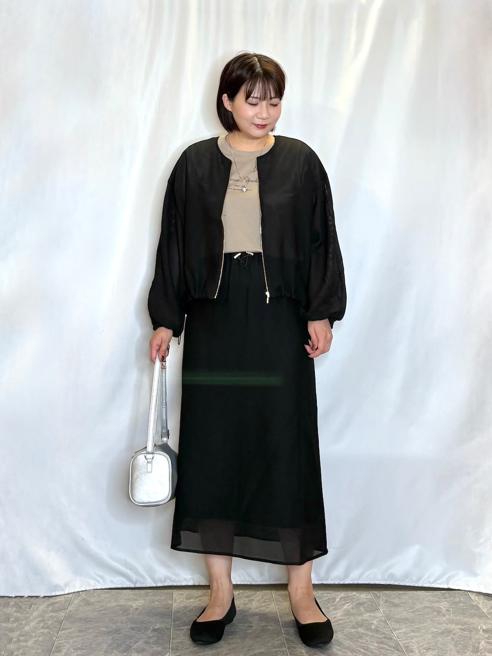 ブラック系のブルゾン、ベージュ系のTシャツ/カットソー、ブラック系のスカートを着用したレディースの夏コーディネートの1枚目の写真