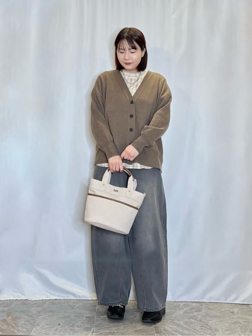 ブラウン系のカーディガン/ボレロ、ベージュ系のシャツ/ブラウス、ブラック系のデニムパンツを着用したレディースの秋コーディネートの1枚目の写真