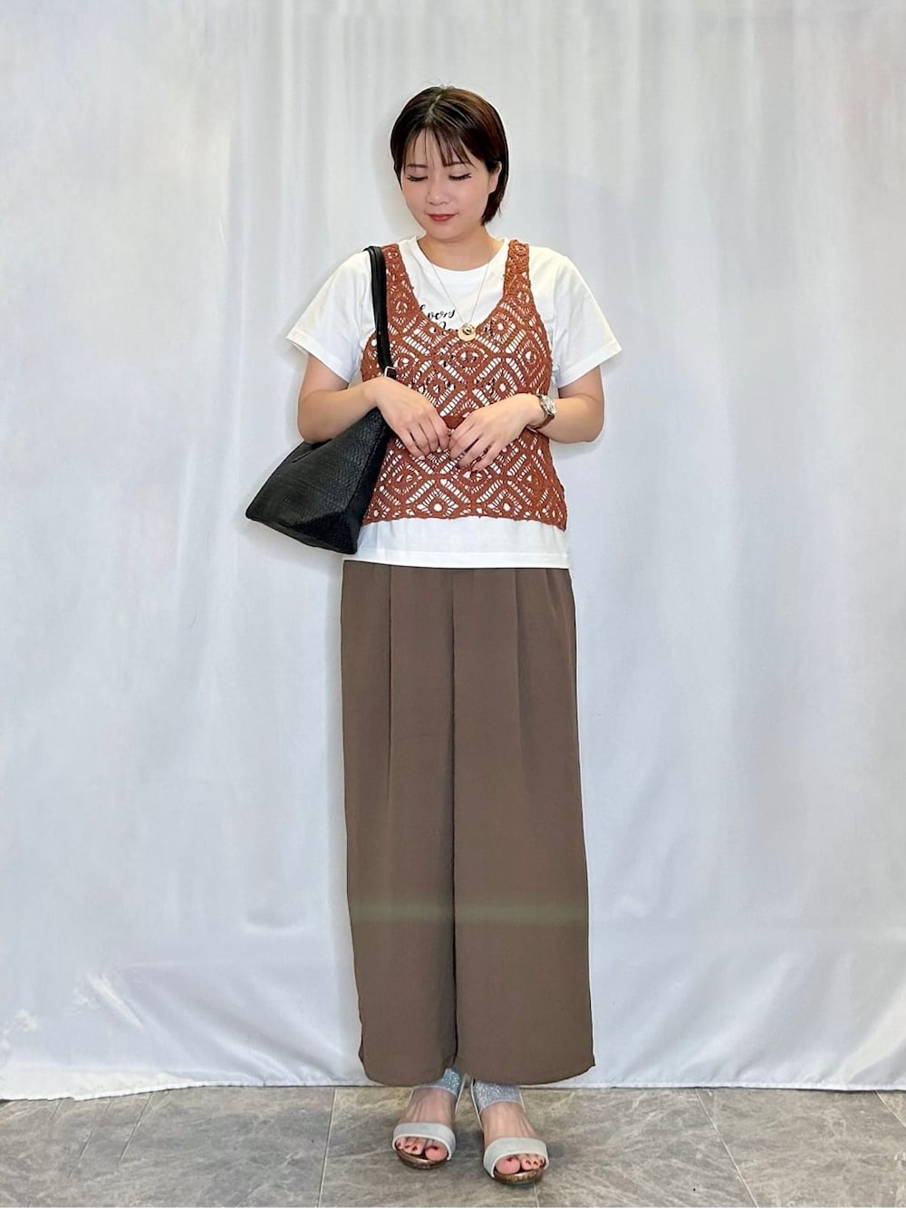 オレンジ系のその他トップス、ブラウン系のその他パンツ、シルバー系のサンダルを着用したレディースの夏コーディネートの1枚目の写真
