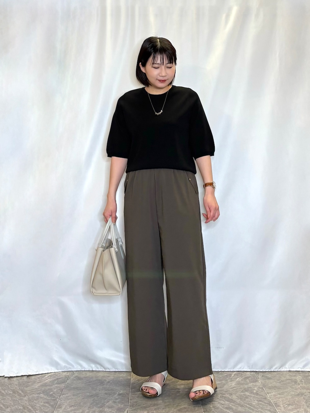 ブラック系のニット/セーター、ブラウン系のその他パンツ、ホワイト系のサンダルを着用したレディースの夏コーディネートの1枚目の写真