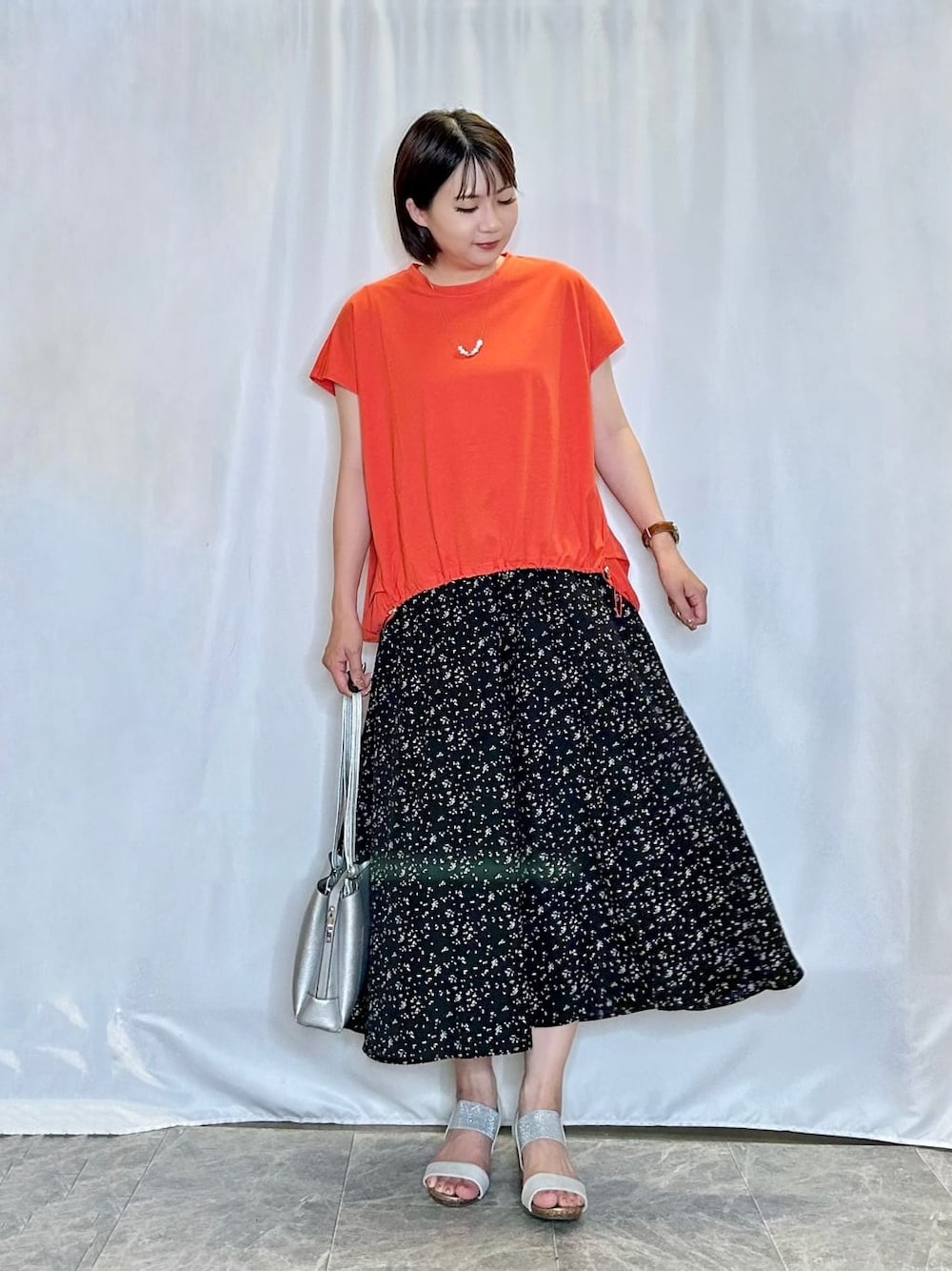 オレンジ系のTシャツ/カットソー、ブラック系のその他パンツ、シルバー系のサンダルを着用したレディースの夏コーディネートの1枚目の写真