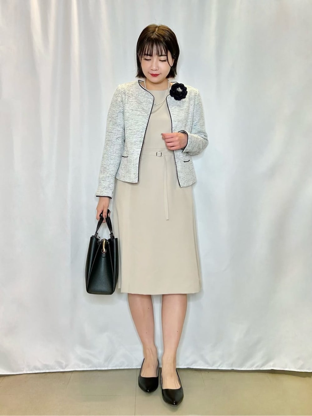 グレー系のノーカラージャケット、ブルー系のブローチ/コサージュを着用したレディースの春コーディネートの1枚目の写真