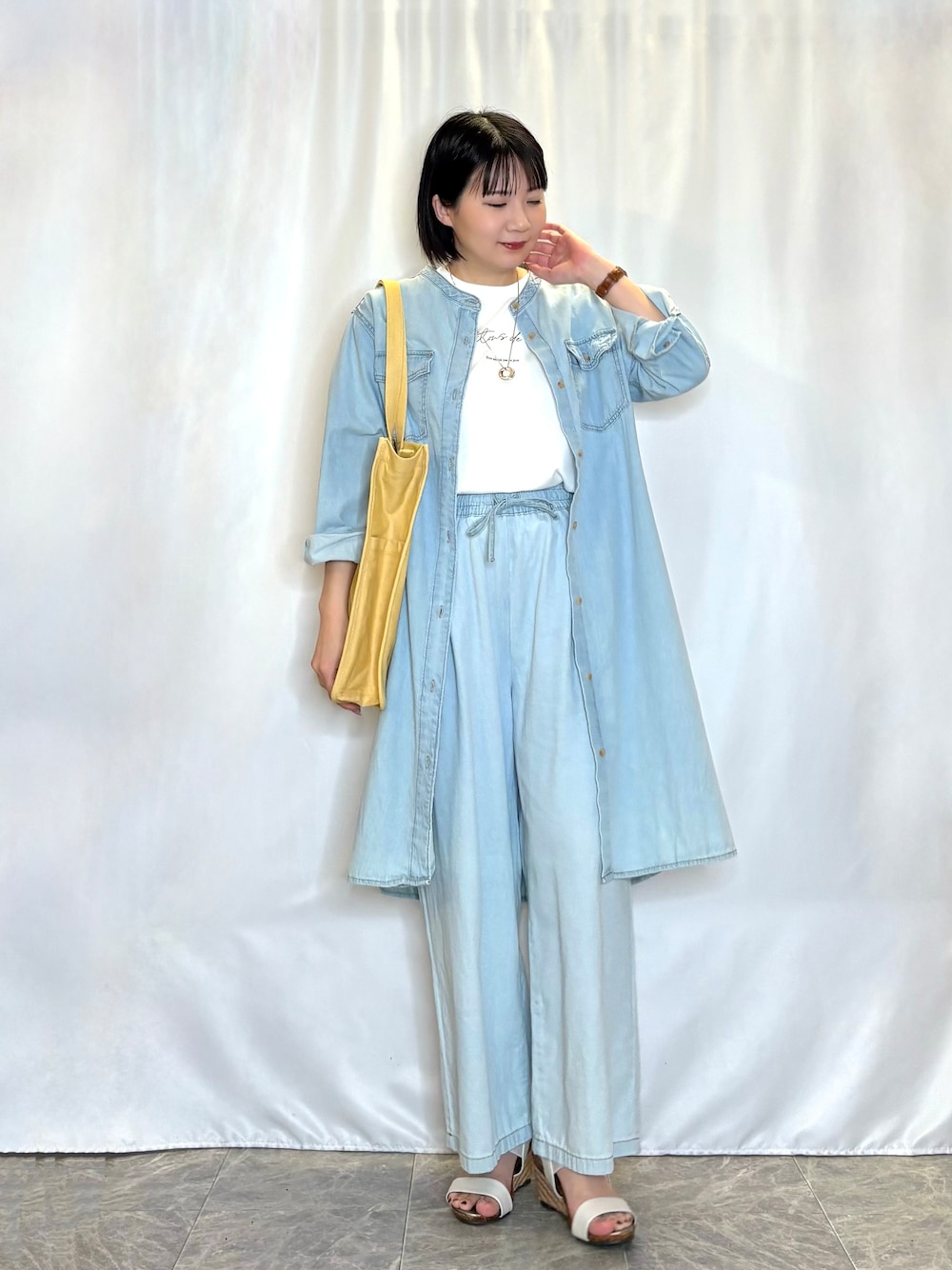 ブルー系のワンピース、ブルー系のデニムパンツ、イエロー系のトートバッグを着用したレディースの春コーディネートの1枚目の写真
