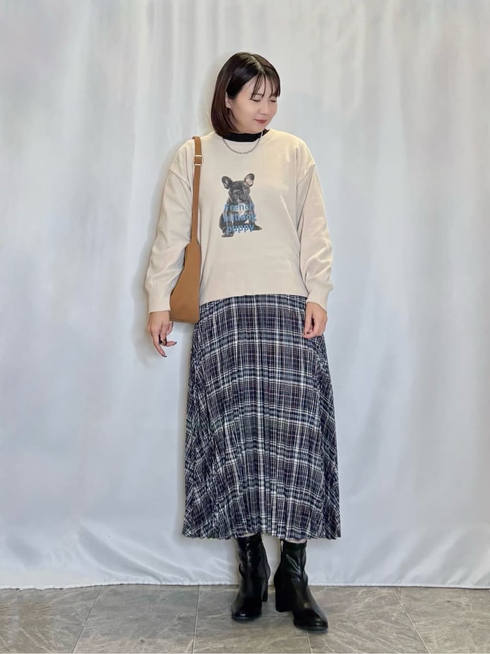 ベージュ系のニット/セーター、ブラック系のTシャツ/カットソー、ブルー系のスカートを着用したレディースの秋コーディネートの1枚目の写真