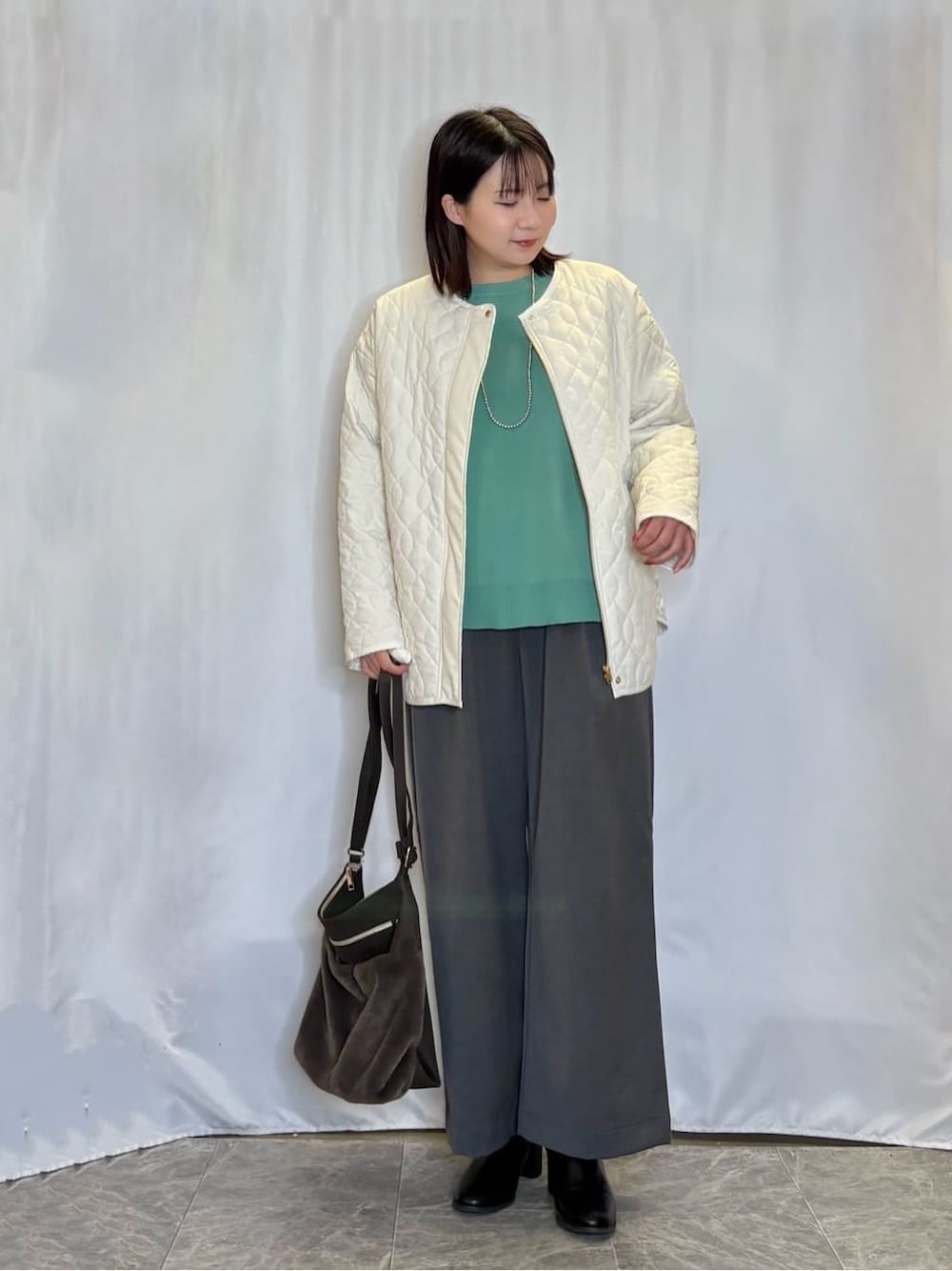 ホワイト系のノーカラージャケット、グリーン系のニット/セーター、グレー系のその他パンツを着用したレディースの冬コーディネートの1枚目の写真
