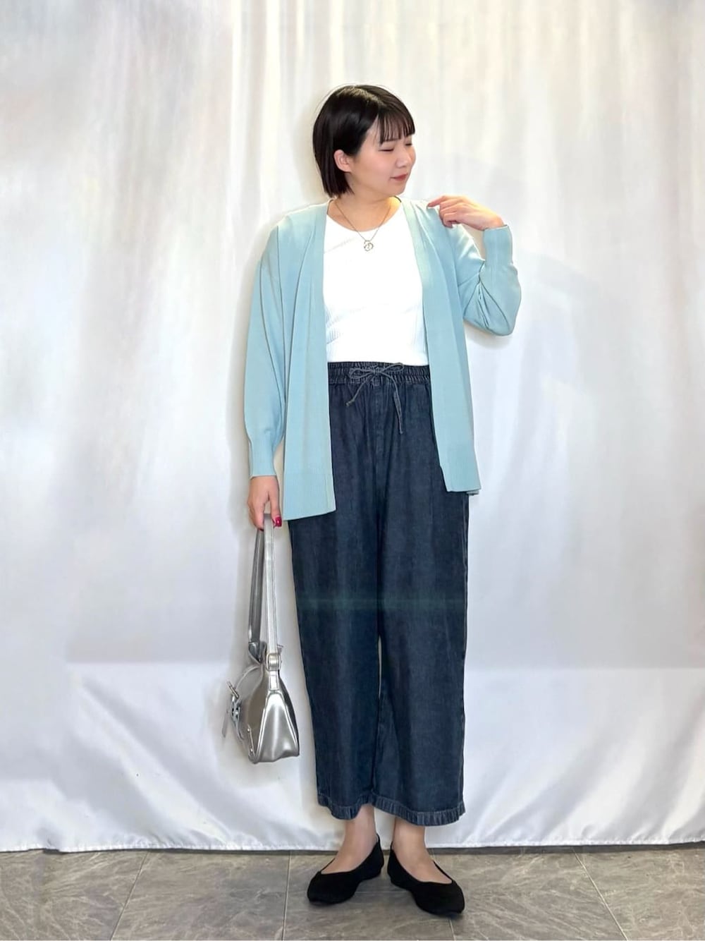 ブルー系のデニムパンツ、ブラック系のワンピース、グリーン系のカーディガン/ボレロを着用したレディースの春コーディネートの1枚目の写真
