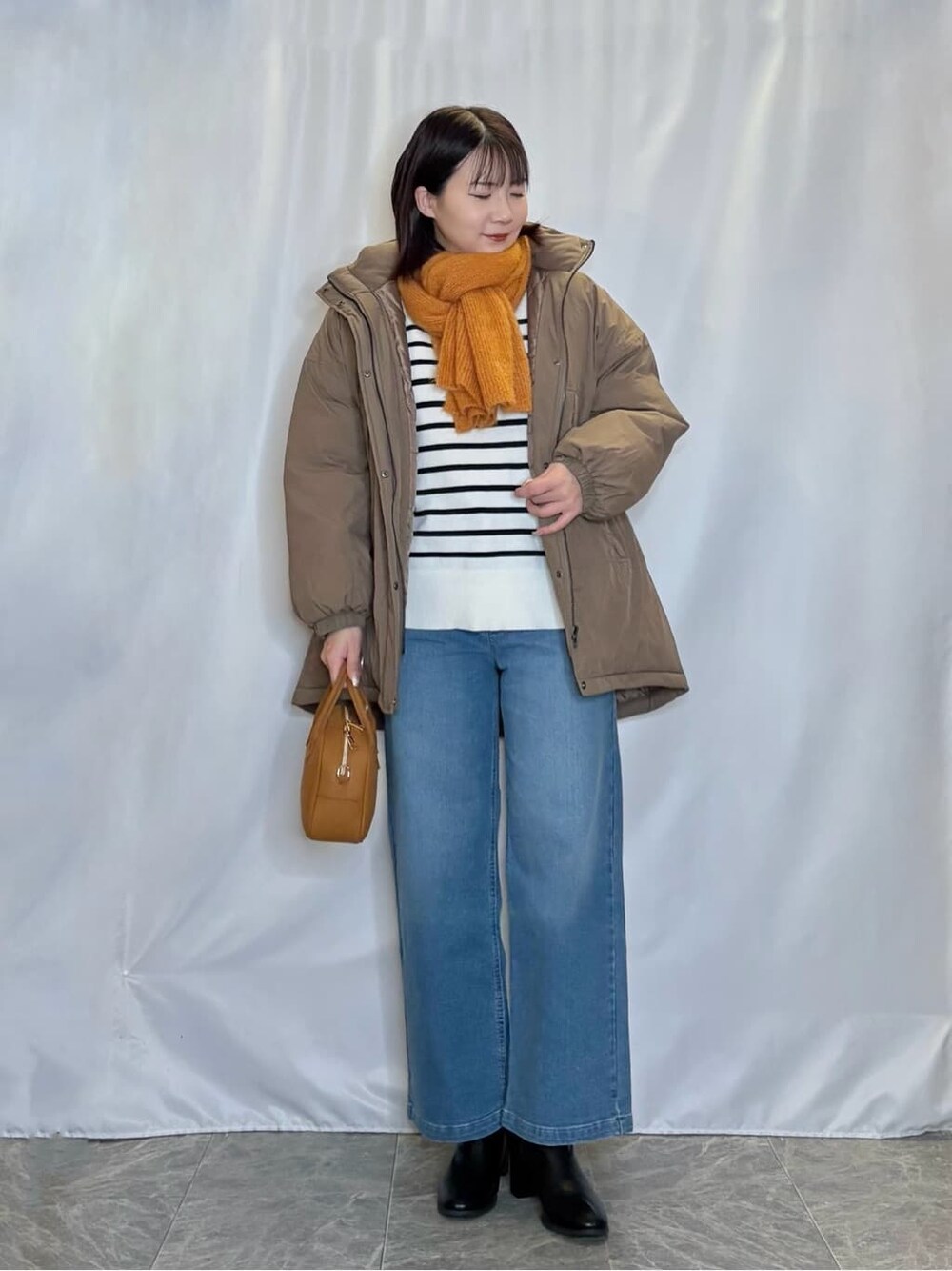 ブラウン系のその他アウター、ホワイト系のニット/セーター、ブルー系のデニムパンツを着用したレディースの冬コーディネートの1枚目の写真
