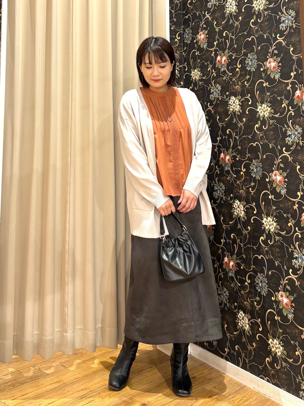 グレー系のカーディガン/ボレロ、オレンジ系のシャツ/ブラウス、グレー系のスカートを着用したレディースの秋コーディネートの1枚目の写真