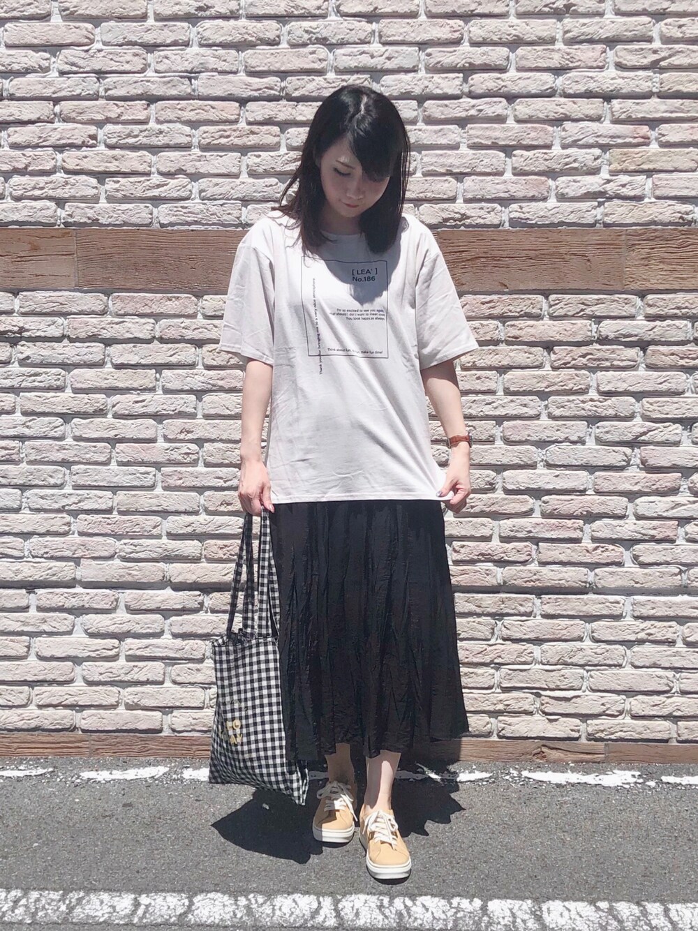 ベージュ系のTシャツ/カットソー、ブラック系のスカート、イエロー系のスニーカーを着用したレディースの夏コーディネートの1枚目の写真