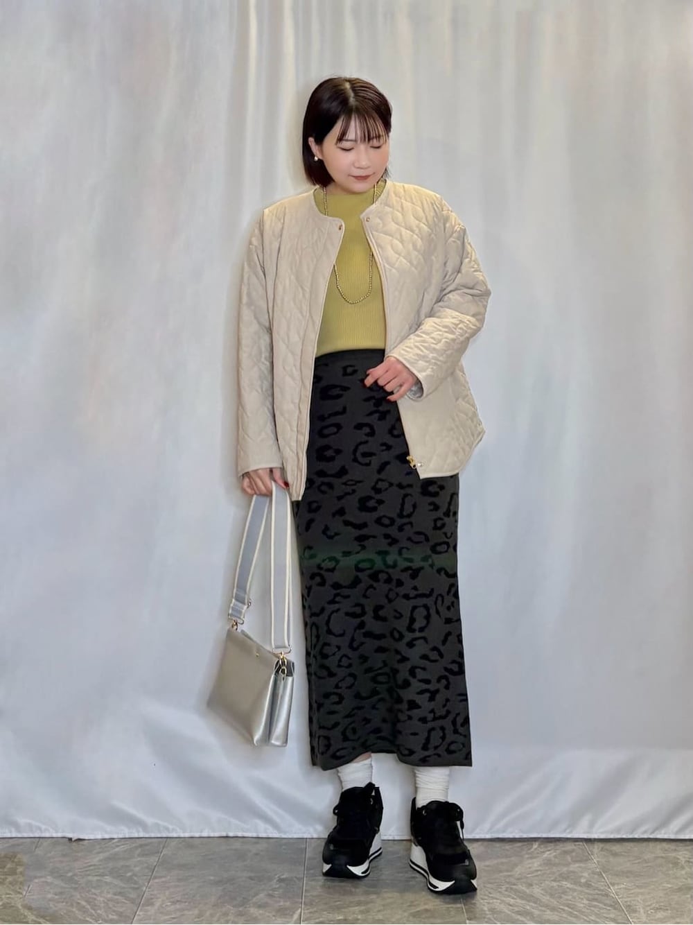 ベージュ系のノーカラージャケット、イエロー系のニット/セーター、グレー系のスカートを着用したレディースの冬コーディネートの1枚目の写真