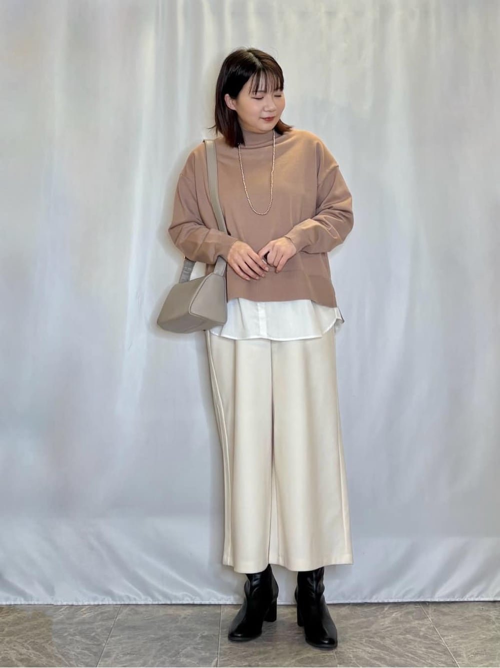 ブラウン系のニット/セーター、ホワイト系のその他パンツ、ブラック系のブーツを着用したレディースの冬コーディネートの1枚目の写真