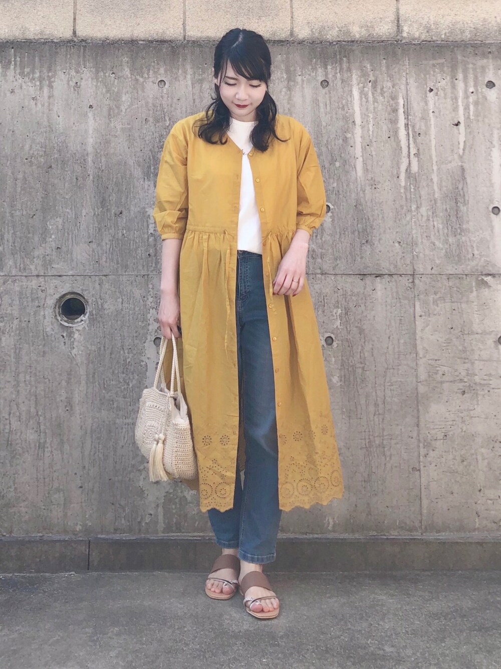 イエロー系のワンピース、ホワイト系のTシャツ/カットソー、ブルー系のデニムパンツを着用したレディースの春コーディネートの1枚目の写真