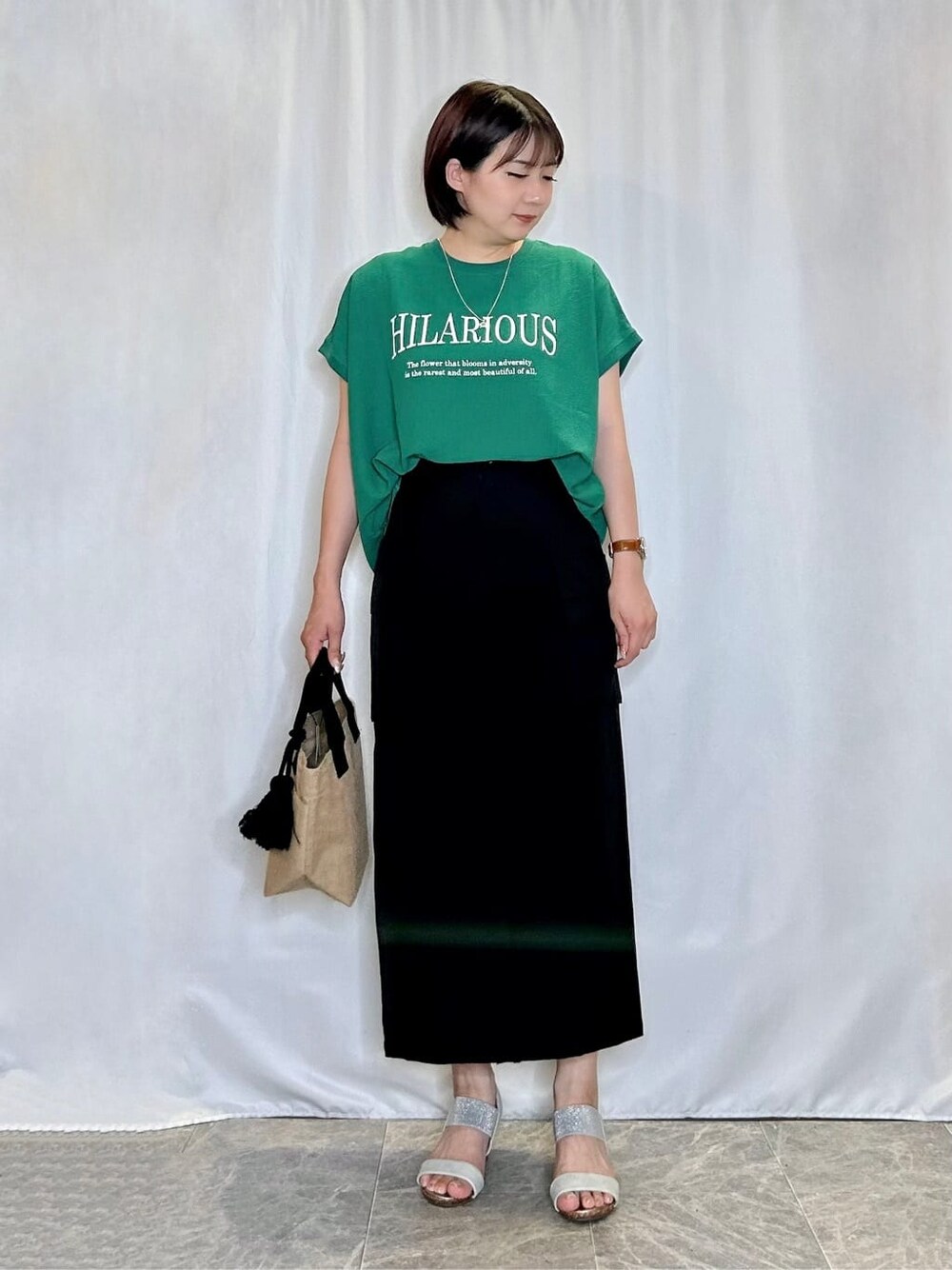 グリーン系のTシャツ/カットソー、ブラック系のスカート、シルバー系のサンダルを着用したレディースの夏コーディネートの1枚目の写真