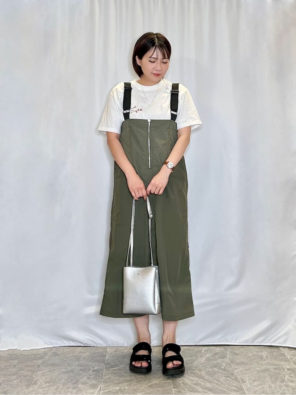 グリーン系のワンピース、ホワイト系のTシャツ/カットソー、ブラック系のサンダルを着用したレディースの夏コーディネートの1枚目の写真