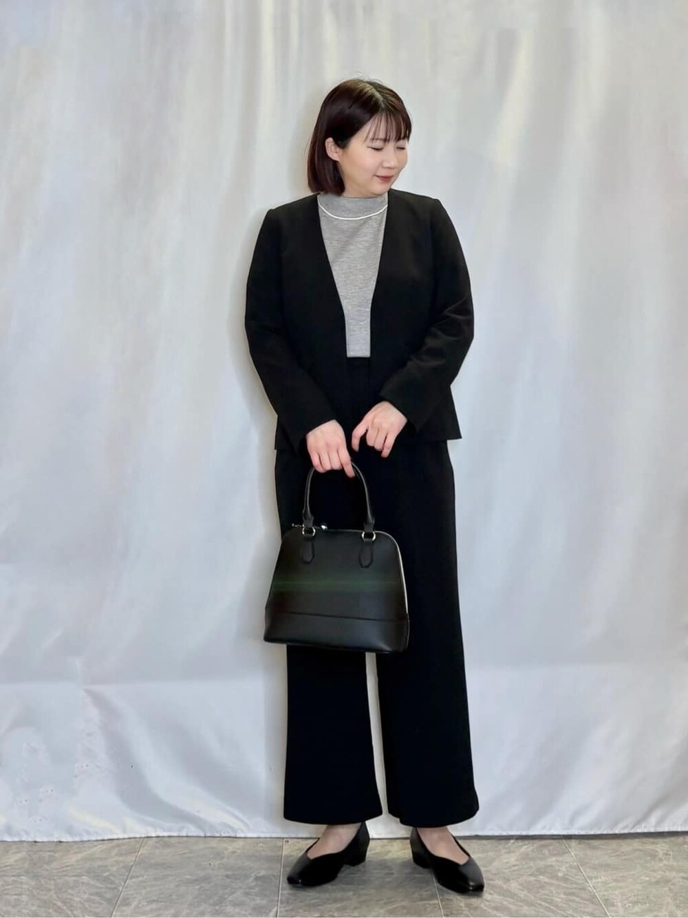ブラック系のノーカラージャケット、ブラック系のその他パンツ、グレー系のニット/セーターを着用したレディースの冬コーディネートの1枚目の写真