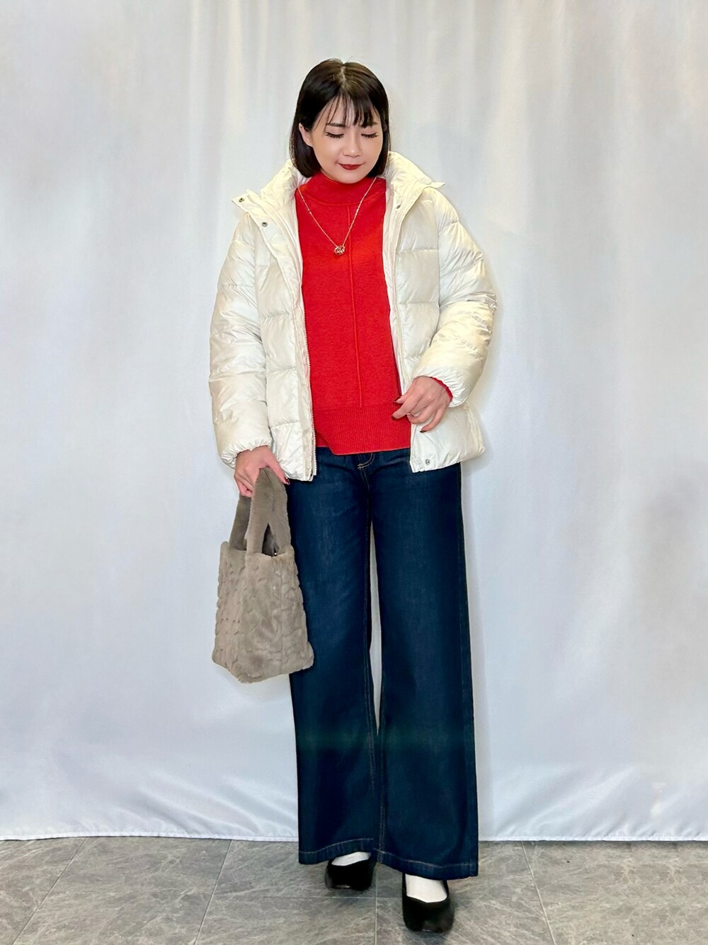 ベージュ系のトートバッグ、ブラック系のパンプス、ブルー系のデニムパンツを着用したレディースの冬コーディネートの1枚目の写真