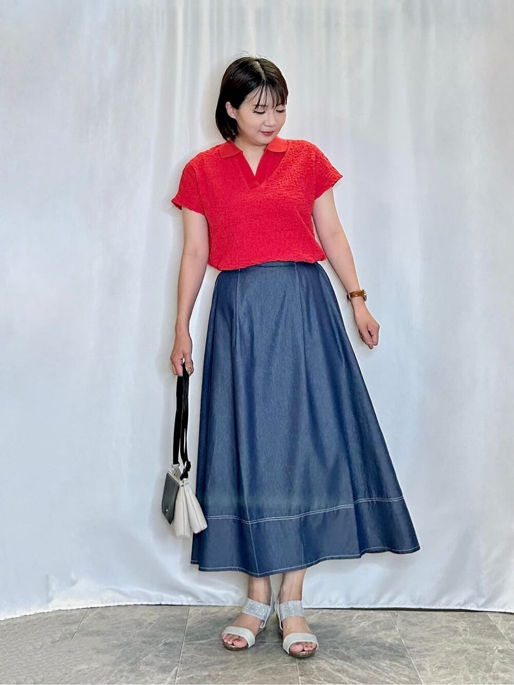 レッド系のTシャツ/カットソー、ブルー系のスカート、シルバー系のサンダルを着用したレディースの夏コーディネートの1枚目の写真