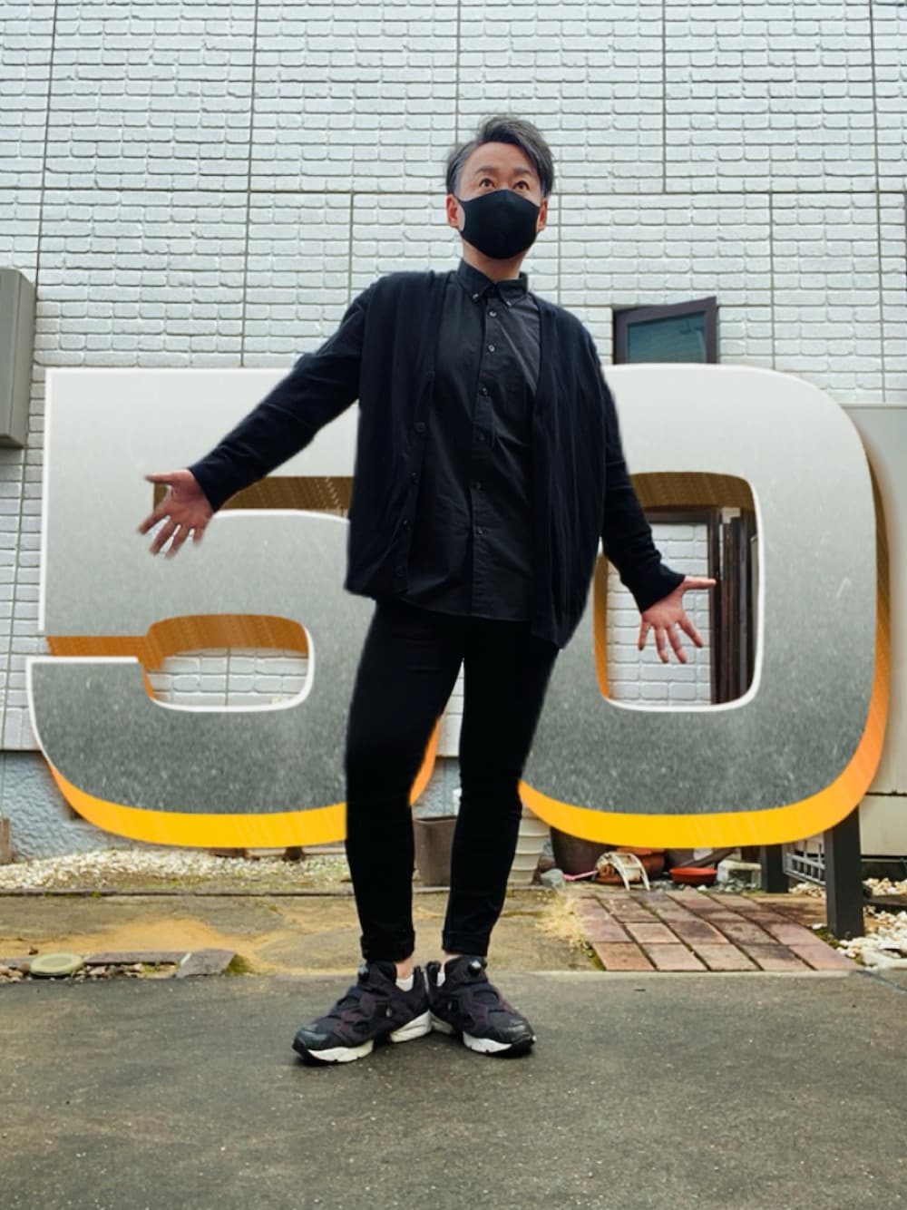 ブラック系のカーディガン/ボレロ、ブラック系のデニムパンツ、ブラック系のスニーカーを着用したメンズの春コーディネートの1枚目の写真